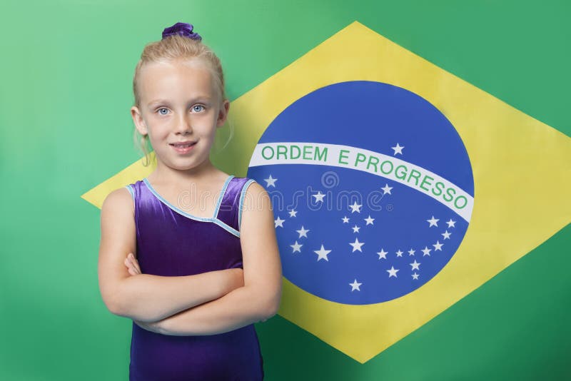 Portretul unei tinere femei de gimnastică fericită cu brațele încrucișate în fața steagului brazilian royalty free stock photography