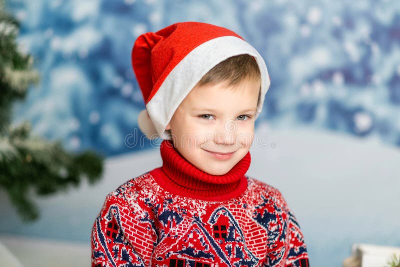 Portretul unui băiețel într-o pălărie de Crăciun și un pulover roșu stock photography