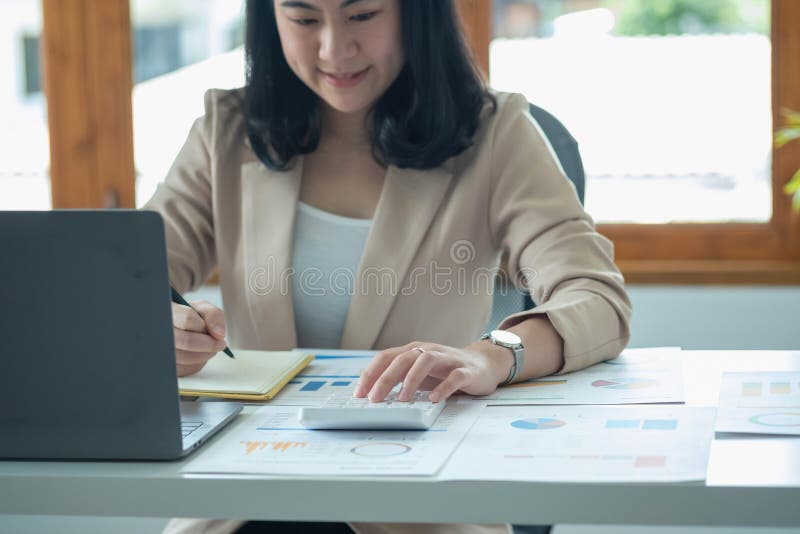 Portretul unui contabil feminin care utilizează un calculator și un laptop pentru a calcula echilibrul utilizând grafice pentru cl stock photos