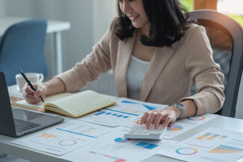 Portretul unui contabil feminin care utilizează un calculator și un laptop pentru a calcula echilibrul utilizând grafice pentru cl royalty free stock image