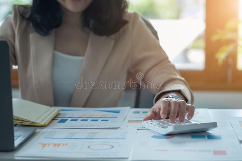 Portretul unui contabil feminin care utilizează un calculator și un laptop pentru a calcula echilibrul utilizând grafice pentru cl royalty free stock photos