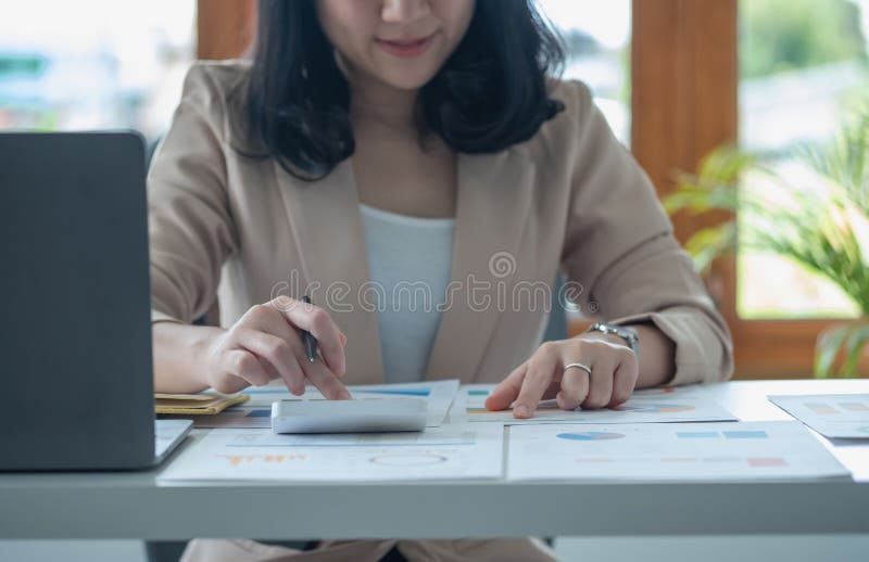 Portretul unui contabil feminin care utilizează un calculator și un laptop pentru a calcula echilibrul utilizând grafice pentru cl stock photos