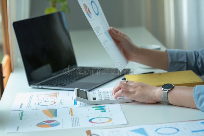 Portretul unui contabil feminin care utilizează un calculator și un laptop pentru a calcula echilibrul utilizând grafice pentru cl royalty free stock image
