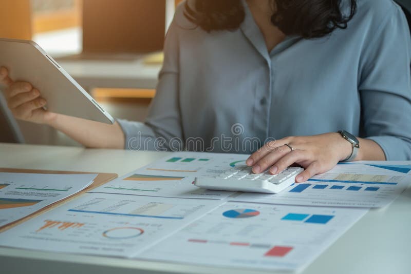 Portretul unui contabil feminin care utilizează un calculator și un laptop pentru a calcula echilibrul utilizând grafice pentru cl royalty free stock photos