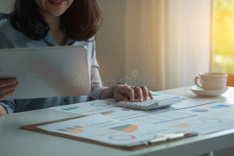Portretul unui contabil feminin care utilizează un calculator și un laptop pentru a calcula echilibrul utilizând grafice pentru cl stock image