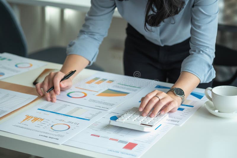 Portretul unui contabil feminin care utilizează un calculator și un laptop pentru a calcula echilibrul utilizând grafice pentru cl royalty free stock image