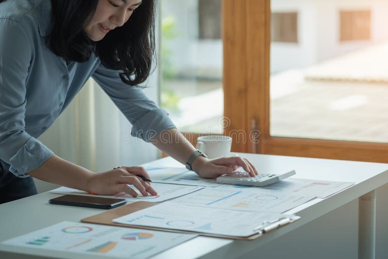 Portretul unui contabil feminin care utilizează un calculator și un laptop pentru a calcula echilibrul utilizând grafice pentru cl stock image
