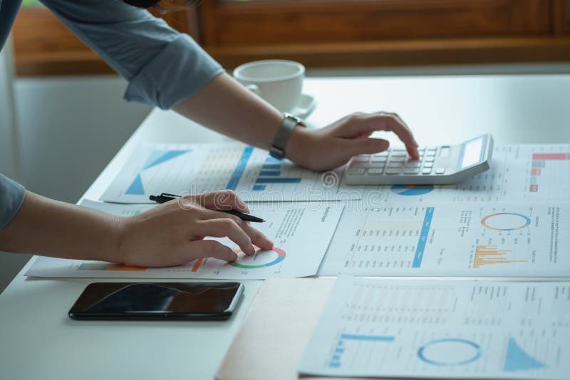 Portretul unui contabil feminin care utilizează un calculator și un laptop pentru a calcula echilibrul utilizând grafice pentru cl royalty free stock photos