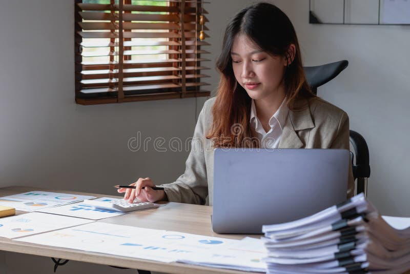 Portretul unui contabil feminin care utilizează un calculator și un laptop pentru a calcula echilibrul utilizând grafice pentru cl stock photography