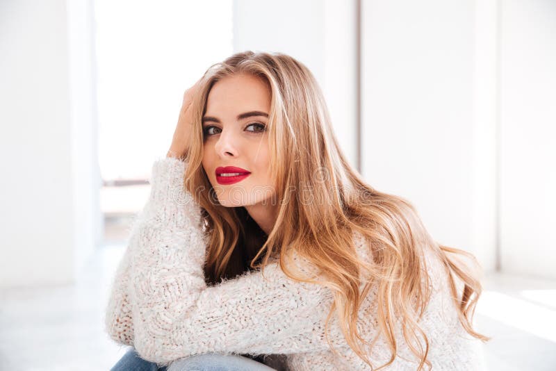 Close up portrait of attractive young woman wearing sweater and red lipstick looking at camera. Close up portrait of attractive young woman wearing sweater and red lipstick looking at camera