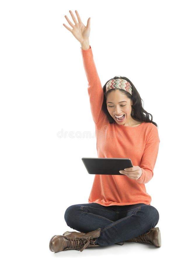 Excited young woman looking at digital tablet while sitting against white background. Excited young woman looking at digital tablet while sitting against white background