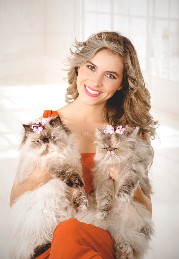 Porträt der eleganten jungen Frau, die zwei entzückende persische Katzen hält stockbild