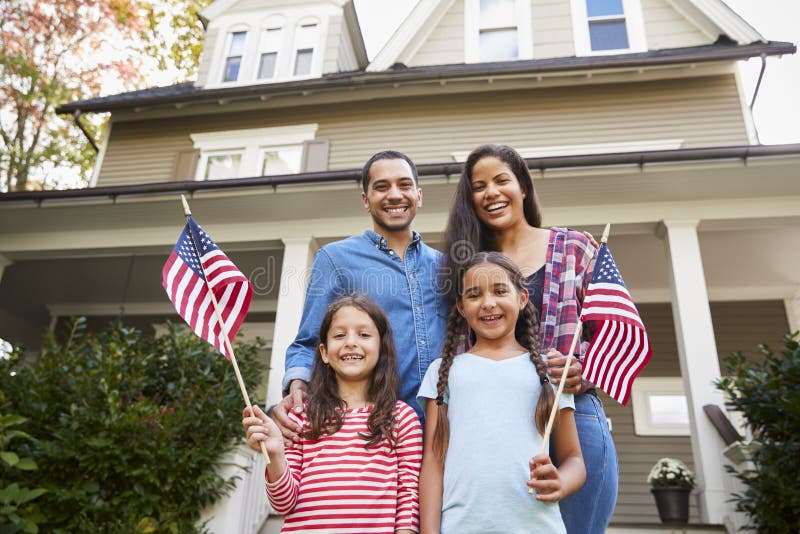 Porträt der Familie außerhalb des Hauses, das amerikanische Flaggen hält lizenzfreie stockfotos Porträt der Familie außerhalb des Hauses, das amerikanische Flaggen hält lizenzfreie stockfotos