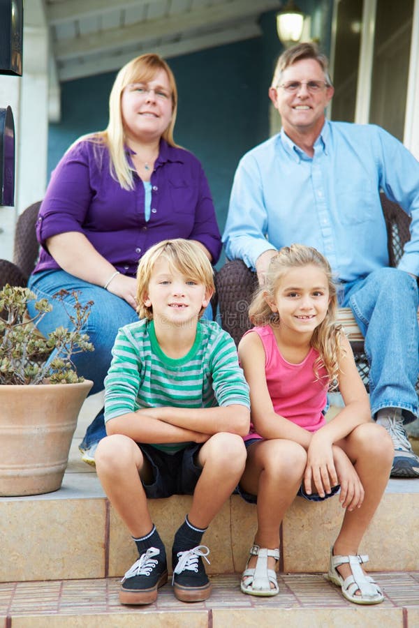 Porträt der Familie sitzend außerhalb des Hauses lizenzfreie stockfotos Porträt der Familie sitzend außerhalb des Hauses lizenzfreie stockfotos