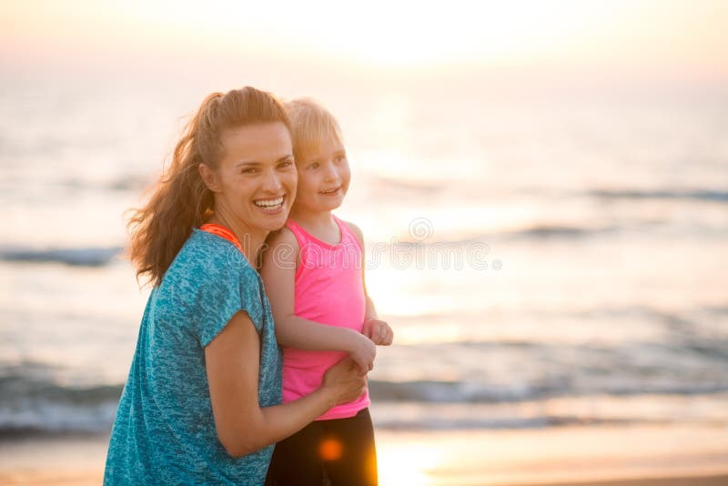 Porträt der glücklichen jungen Mutter und der Tochter auf Strand bei Sonnenuntergang stockbilder Porträt der glücklichen jungen Mutter und der Tochter auf Strand bei Sonnenuntergang stockbilder