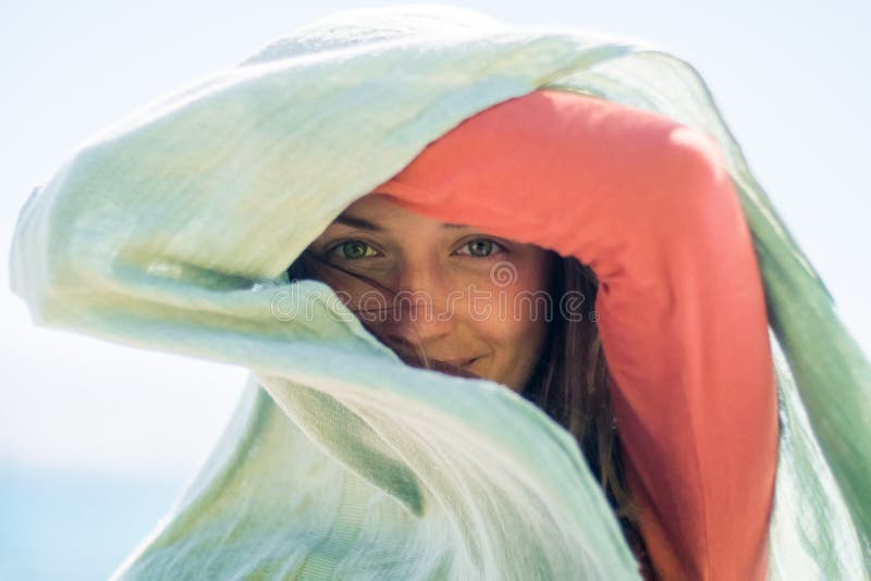 Porträt der glücklichen lächelnden jungen Frau mit dem langen Haar Sie versteckt und stellt einen Schatten mit Schal her stockfotografie Porträt der glücklichen lächelnden jungen Frau mit dem langen Haar Sie versteckt und stellt einen Schatten mit Schal her stockfotografie