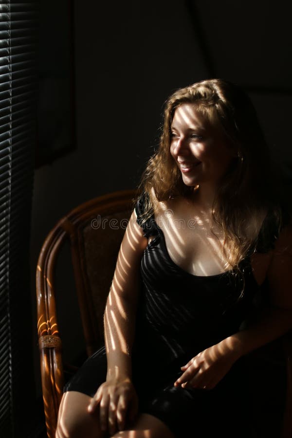 Porträt der jungen hübscher Frau sitzt im Stuhl, gestreifte Schatten