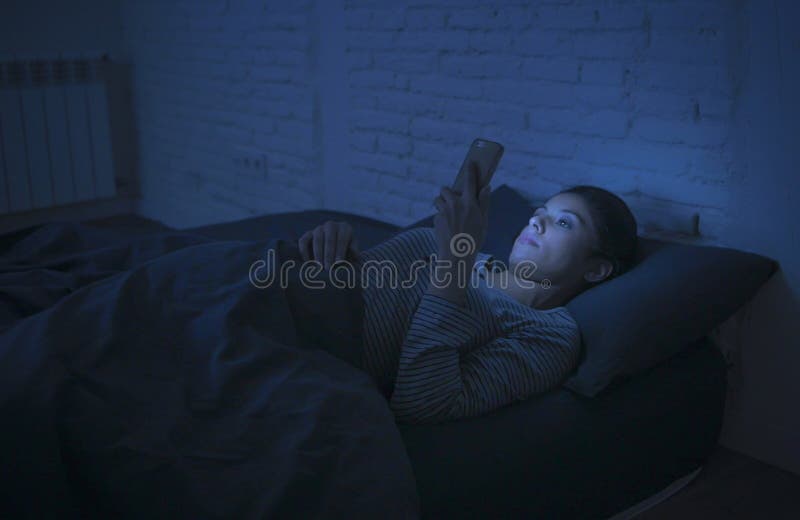 Porträt der jungen schönen lateinischen Frau, die das Spät- schlaflose Lügen des Handys im Bett in der Dunkelheit im Smartphone u stockfotos Porträt der jungen schönen lateinischen Frau, die das Spät- schlaflose Lügen des Handys im Bett in der Dunkelheit im Smartphone u stockfotos