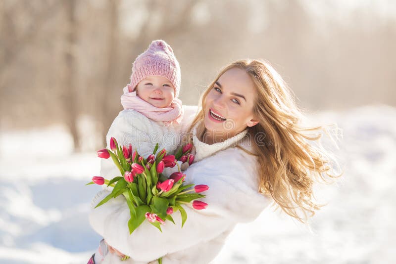 Porträt der lächelnden jungen Mutter mit einem Baby in Hände am sonnigen Tag des Winters lizenzfreie stockbilder Porträt der lächelnden jungen Mutter mit einem Baby in Hände am sonnigen Tag des Winters lizenzfreie stockbilder