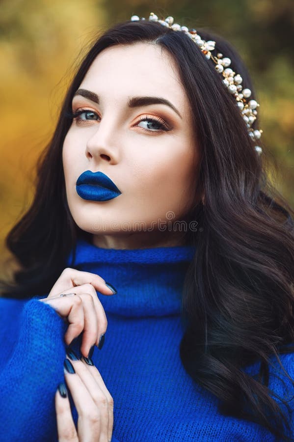Porträt der schönen jungen Frau mit den blauen Lippen und blauer Strickjacke mit Zusatz auf ihrem Kopf im Park stockfotos Porträt der schönen jungen Frau mit den blauen Lippen und blauer Strickjacke mit Zusatz auf ihrem Kopf im Park stockfotos