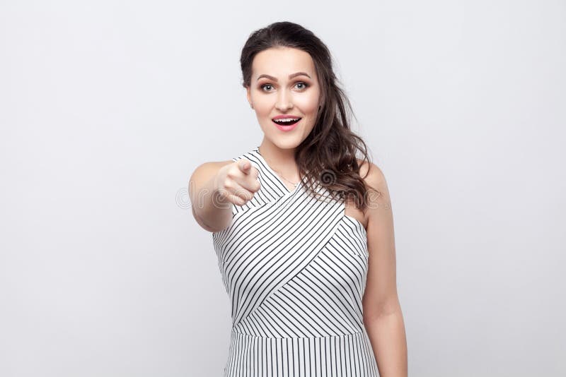 Porträt der überraschten glücklichen schönen jungen brunette Frau mit Make-up und gestreifter Kleiderstellung, betrachtend und ze lizenzfreie stockfotografie Porträt der überraschten glücklichen schönen jungen brunette Frau mit Make-up und gestreifter Kleiderstellung, betrachtend und ze lizenzfreie stockfotografie