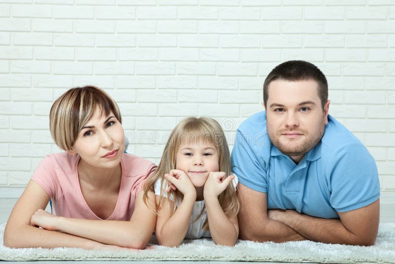 Porträt des Babys und ihre Eltern, die auf Teppich im Wohnzimmer liegen stockfotografie Porträt des Babys und ihre Eltern, die auf Teppich im Wohnzimmer liegen stockfotografie