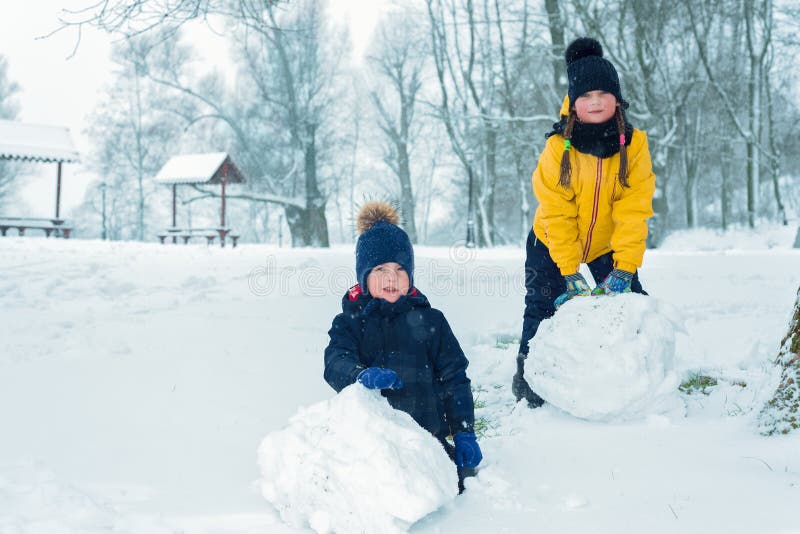 Porträt des Bruders und der Schwester wenig Junge und Mädchen machen Schneemann lizenzfreie stockbilder