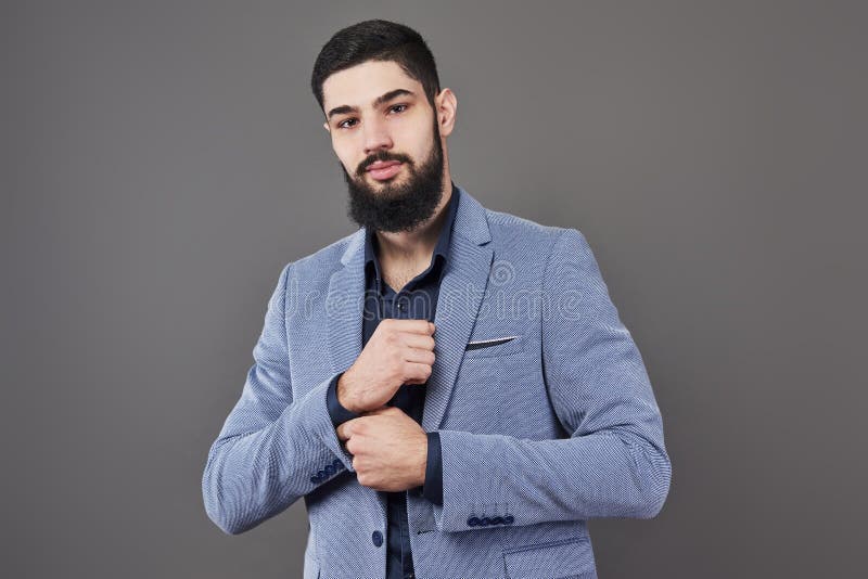 Porträt des Freiberuflermannes mit Bart in der Jacke, die gegen grauen Hintergrund steht stockfotos Porträt des Freiberuflermannes mit Bart in der Jacke, die gegen grauen Hintergrund steht stockfotos