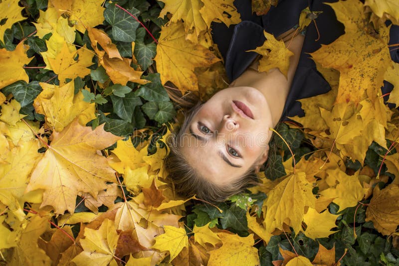 Porträt des jungen schönen Mädchens, das auf dem Herbstlaub liegt stockfoto Porträt des jungen schönen Mädchens, das auf dem Herbstlaub liegt stockfoto