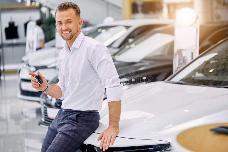 Portrait of happy caucasian client man buying new car in car store. luxurious white car is on exhibition in dealership. Portrait of happy caucasian client man buying new car in car store. luxurious white car is on exhibition in dealership