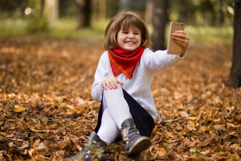 Porträt des lustigen kleinen Gesichtes verziehendes Mädchens beim Nehmen von selfie in Herbst stockbild Porträt des lustigen kleinen Gesichtes verziehendes Mädchens beim Nehmen von selfie in Herbst stockbild