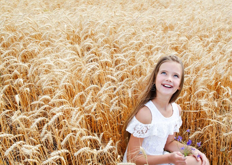 Porträt des lächelnden netten Kindes des kleinen Mädchens auf dem Feld des Weizens Blumen halten lizenzfreies stockbild Porträt des lächelnden netten Kindes des kleinen Mädchens auf dem Feld des Weizens Blumen halten lizenzfreies stockbild