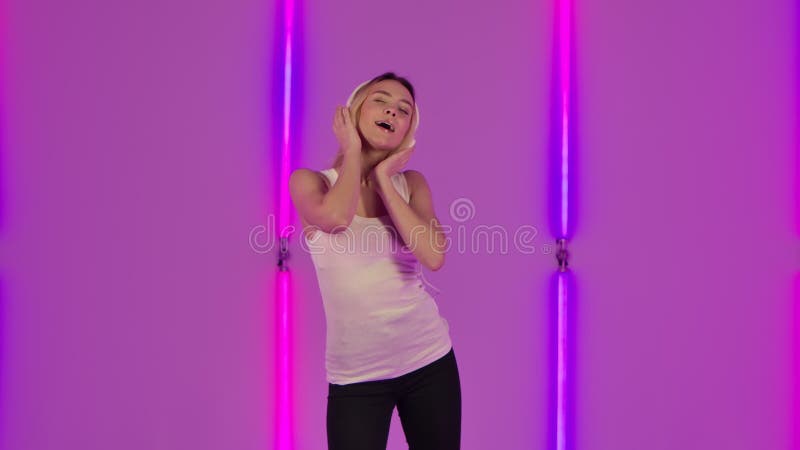 Porträt des modernen Modells genießen, tanzen und Musik in den großen weißen Kopfhörern. junge Blondine in Weiß zufälligem stock video