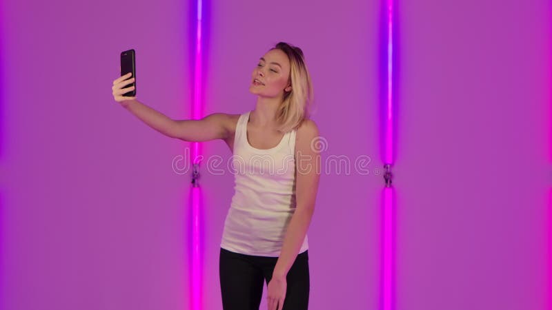 Porträt des modernen Modells Sicht für Videochat mithilfe des Handys und freuen sich. junge Blondine in Weiß zufälligem stock video
