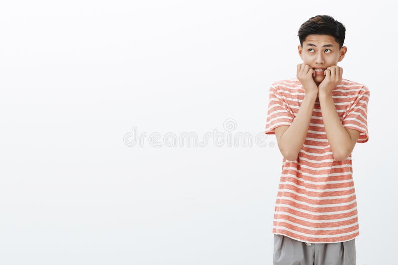 Porträt des nervösen und erschrockenen jungen asiatischen Jungen in gestreiftes T-Shirt beißenden Fingern, welche die obere linke lizenzfreies stockfoto Porträt des nervösen und erschrockenen jungen asiatischen Jungen in gestreiftes T-Shirt beißenden Fingern, welche die obere linke lizenzfreies stockfoto