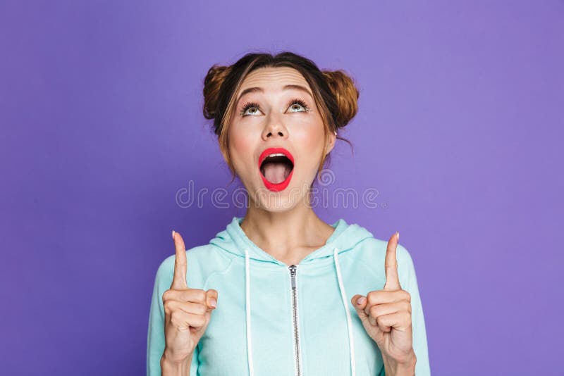 Porträt des netten brunette Mädchens mit zwei Brötchen Finger zeigend lizenzfreies stockfoto