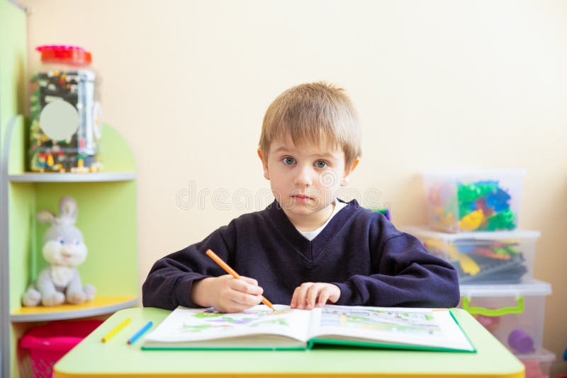 Porträt des netten Jungen mit Skizzenstift und des Buches am Schreibtisch im Klassenzimmer stockbilder Porträt des netten Jungen mit Skizzenstift und des Buches am Schreibtisch im Klassenzimmer stockbilder