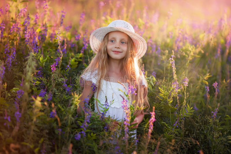 Porträt des netten jungen Mädchens mit dem langen Haar in einem Hut bei Sonnenuntergang