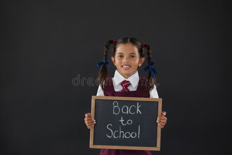 Porträt des Schulmädchens Schiefer mit Text gegen Tafel halten