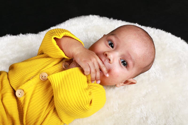 Porträt des seltsamen Babys liegend auf Rücken Weiß Felle stockfotos