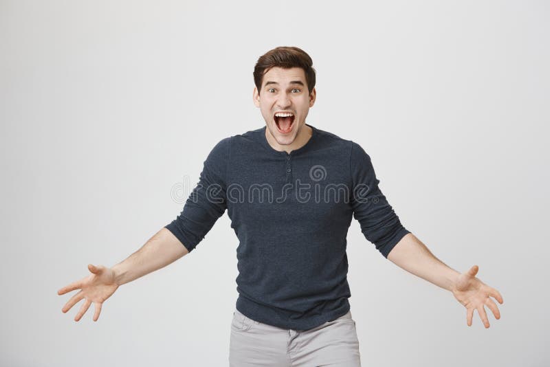 Porträt des zu aufgeregten jungen europäischen Mannes, ausgebreitete Arme und das Schreien mit verbreitern Augen an der Kamera un lizenzfreies stockbild Porträt des zu aufgeregten jungen europäischen Mannes, ausgebreitete Arme und das Schreien mit verbreitern Augen an der Kamera un lizenzfreies stockbild