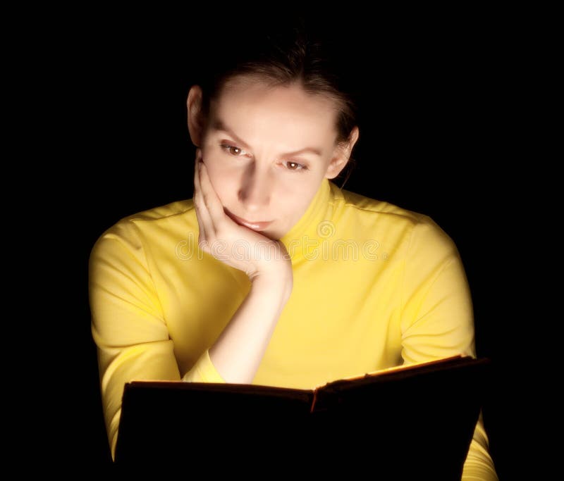 Portrait of an attractive beautiful pretty cute young brown haired caucasian woman (lady, girl, female, person, model) dressed in yellow reading glowing lighting magic book with attention. Isolated on black background (backdrop) with blank copy space. Portrait of an attractive beautiful pretty cute young brown haired caucasian woman (lady, girl, female, person, model) dressed in yellow reading glowing lighting magic book with attention. Isolated on black background (backdrop) with blank copy space.