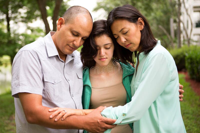 Porträt einer Familie, die mit ihrer Tochter betet stockfotos Porträt einer Familie, die mit ihrer Tochter betet stockfotos