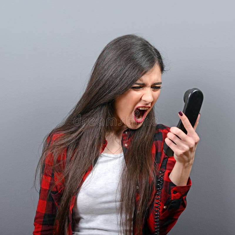 Porträt einer Frau, die am Telefon gegen grauen Hintergrund schreit lizenzfreies stockfoto Porträt einer Frau, die am Telefon gegen grauen Hintergrund schreit lizenzfreies stockfoto