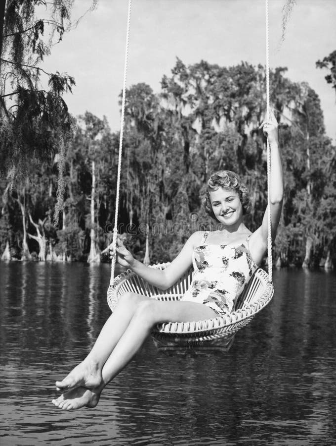 Porträt einer jungen Frau, die auf einem Schwingen am Seeufer sitzt und Lächeln (alle dargestellten Personen sind nicht längeres