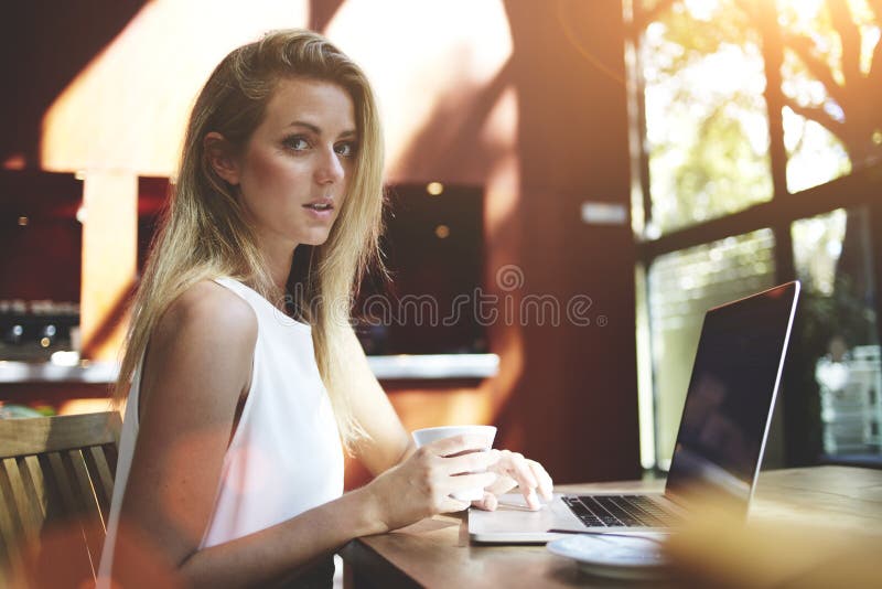 Porträt einer jungen schönen Schweden-Frau, die Laptop-Computer verwendet, beim Sitzen in der modernen Kaffeestube, stockbild Porträt einer jungen schönen Schweden-Frau, die Laptop-Computer verwendet, beim Sitzen in der modernen Kaffeestube, stockbild
