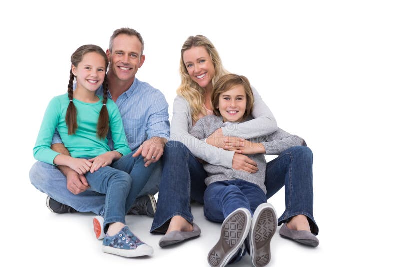 Porträt einer lächelnden Familie, die auf dem Boden sitzt stockfotografie Porträt einer lächelnden Familie, die auf dem Boden sitzt stockfotografie