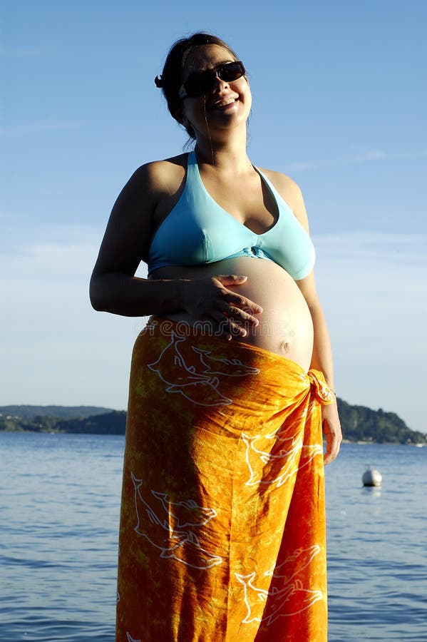 Porträt einer schwangeren Frau mit 30 Jährigen im Strandkostüm