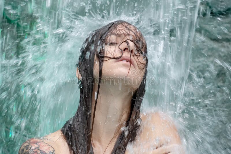 Porträt einer schönen jungen Frau unter dem Wasserfallspritzwasser im Pool stockbilder Porträt einer schönen jungen Frau unter dem Wasserfallspritzwasser im Pool stockbilder
