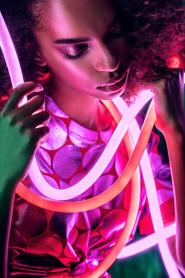 Porträt einer sensualen Afrikanerin mit rosa Neonlicht um das Gesicht lizenzfreie stockfotos Porträt einer sensualen Afrikanerin mit rosa Neonlicht um das Gesicht lizenzfreie stockfotos